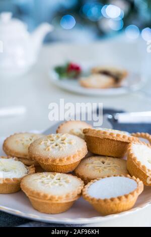 Anglais fête traditionnelle pâtisserie mince pies on servi à table avec l'heure du thé allégé arbre de Noël sur l'arrière-plan. Maison chaleureuse ambiance. Carte verticale. Banque D'Images