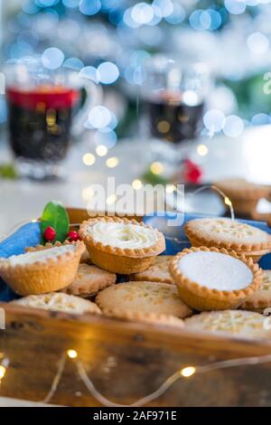 Composition de confortable chaud gentil anglais fête traditionnelle pâtisserie mince pies en plateau en bois avec du vin et des boissons light garland sur accueil table wit Banque D'Images