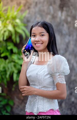 Un jeune Khmer (cambodgien) femme en utilisant son téléphone portable au Cambodge Banque D'Images