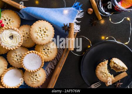 Vue de dessus de la composition confortable chaud anglais fête traditionnelle pâtisserie mince pies dans le bac en bois, d'épices, la plaque noire avec des feux à secteurs et Garland Banque D'Images