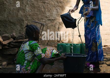 Gros plan d'enfants noirs africains verser de l'eau d'un puits dans la benne Banque D'Images