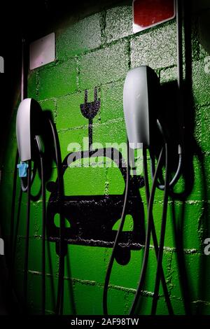 La station de recharge de véhicules électriques, place de parking gratuite sur le mur peint de couleur verte symbole close up, aucun peuple, vertical image Banque D'Images