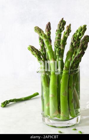 Asperges fraîchement coupées dans un pot en verre rempli d'eau. Banque D'Images