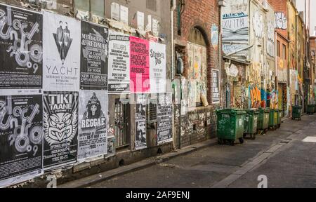 Melbourne, Australie - Novembre 17, 2009 : Ruelle avec mur plâtré avec cas les affiches en noir et blanc et de graffitis, les poubelles vertes et je Banque D'Images