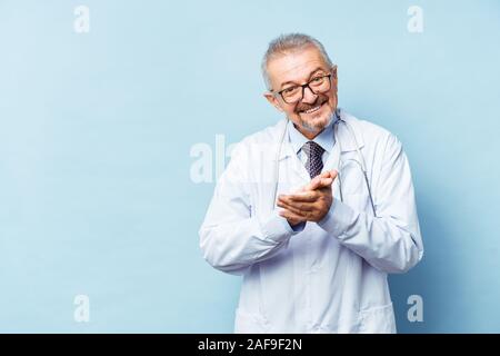 Smiling medical médecin avec un stéthoscope. Sur un fond bleu. Montre infirmier fait lever le pouce. Le concept de l'humanité la victoire sur la maladie Banque D'Images