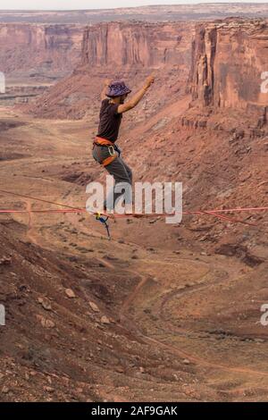 Un jeune homme slackline ou highlining des centaines de pieds au-dessus du Canyon de minéraux près de Moab, en Utah pendant un rassemblement highline. Banque D'Images