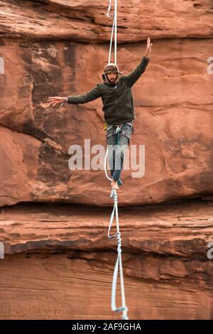 Un jeune homme slackline ou highlining des centaines de pieds au-dessus du Canyon de minéraux près de Moab, en Utah pendant un rassemblement highline. Banque D'Images