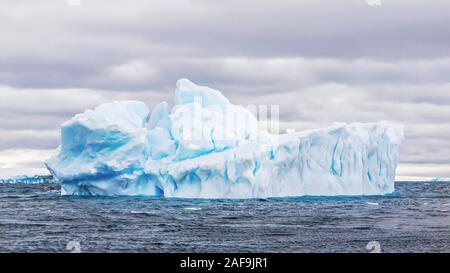 Un gros iceberg flottant dans la mer de Weddell en Antarctique, montrant sa forme naturelle, le bleu de la glace, et des fissures profondes dans sa structure. Banque D'Images