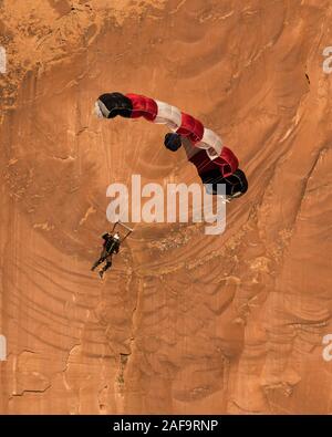 Un cavalier BASE descend dans son parachute au large de la face verticale de 400 pieds de la pierre tombale dans Kane Springs Canyon près de Moab, Utah. Banque D'Images