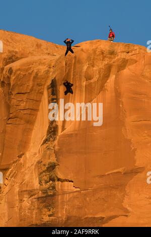 Un pas de géant vers le sommet de la face verticale de 400 pieds de la pierre tombale dans Kane Springs Canyon près de Moab, Utah. Remarque son ombre sur la falaise. Banque D'Images