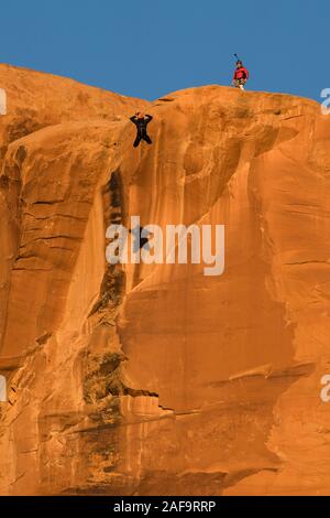 Un pas de géant vers le sommet de la face verticale de 400 pieds de la pierre tombale dans Kane Springs Canyon près de Moab, Utah. Remarque son ombre sur la falaise. Banque D'Images