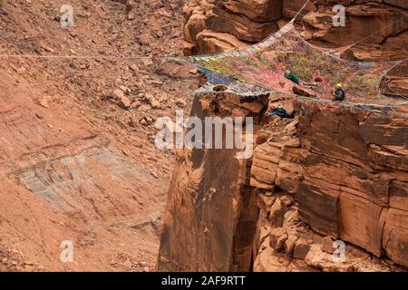 Une femelle cavalier BASE de sauts le ravitailleur Espace Net suspendu de la falaise verticale de 950 pieds au-dessus de la vallée à minéral Canyon près de Moa Banque D'Images