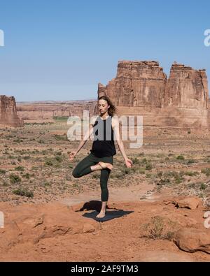 Une jolie jeune femme pratique le yoga à Montagnes La Sal oublier dans Arches National Park près de Moab, Utah. Banque D'Images