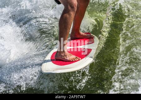 Un jeune homme service surf derrière un bateau sur le Lac Powell, dans le Glen Canyon National Recreation Area dans le sud de l'Utah, USA. Banque D'Images