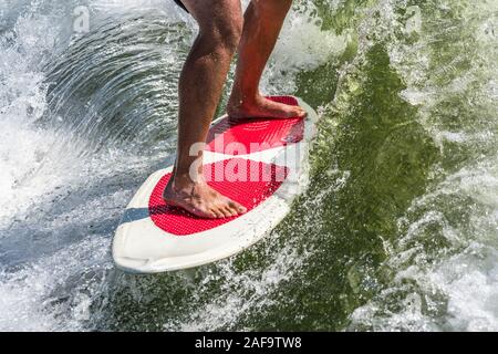 Un jeune homme service surf derrière un bateau sur le Lac Powell, dans le Glen Canyon National Recreation Area dans le sud de l'Utah, USA. Banque D'Images