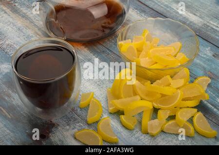 Marmelade de tranches de citron, un verre de thé noir et d'une théière avec thé infusé sur un fond de bois. Dessert sucré. Close up Banque D'Images