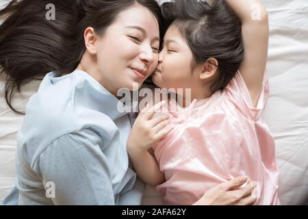 Fille l'embrasse la joue de la mère. et s'étreindre dans la chambre .Happy Asian family Banque D'Images