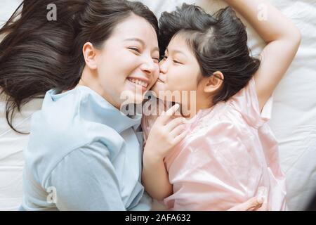 Fille l'embrasse la joue de la mère. et s'étreindre dans la chambre .Happy Asian family Banque D'Images