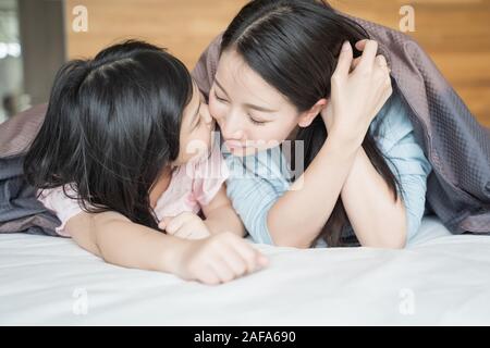 Fille l'embrasse la joue de la mère. et s'étreindre dans la chambre .Happy Asian family Banque D'Images