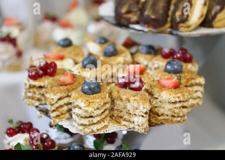 Minis gâteaux décorés avec de la crème fouettée et de groseille rouge. Sweet de savoureux en-cas à la partie. La photographie culinaire. Beaucoup de morceaux de pâte sur la plaque. Banque D'Images