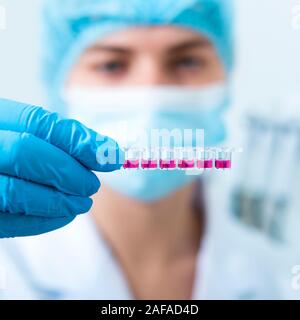 Femme lurred en masque et des gants en latex de la préparation des échantillons pour essais machine rose Banque D'Images