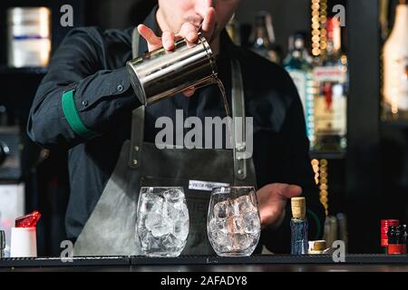 Faire barman cocktail reposant sur un arrière-plan de la barre Banque D'Images