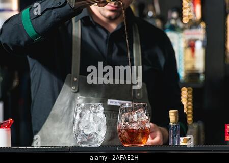 Faire barman cocktail reposant sur un arrière-plan de la barre Banque D'Images