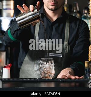 Faire barman cocktail reposant sur un arrière-plan de la barre Banque D'Images