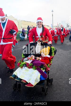 Brighton UK 14 décembre 2019 - Des centaines y compris les enfants et les chiens prennent part à la Brighton Santa Dash sur un jour de vent le long de la mer d'aider à recueillir des fonds pour la charité Rockinghorse qui est le bras de collecte de fonds de l'Hôpital Royal Alexandra d'enfants . Crédit : Simon Dack / Alamy Live News Banque D'Images