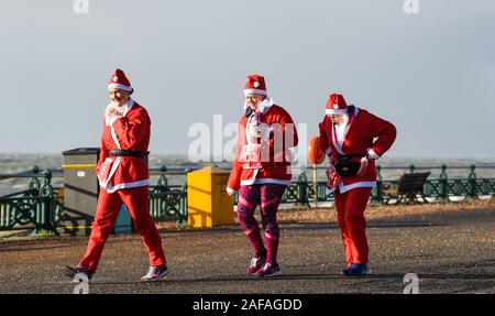 Brighton UK 14 décembre 2019 - Des centaines y compris les enfants et les chiens prennent part à la Brighton Santa Dash sur un jour de vent le long de la mer d'aider à recueillir des fonds pour la charité Rockinghorse qui est le bras de collecte de fonds de l'Hôpital Royal Alexandra d'enfants . Crédit : Simon Dack / Alamy Live News Banque D'Images