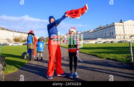 Brighton UK 14 décembre 2019 - Des centaines y compris les enfants et les chiens prennent part à la Brighton Santa Dash sur un jour de vent le long de la mer d'aider à recueillir des fonds pour la charité Rockinghorse qui est le bras de collecte de fonds de l'Hôpital Royal Alexandra d'enfants . Crédit : Simon Dack / Alamy Live News Banque D'Images