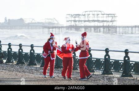 Brighton UK 14 décembre 2019 - Des centaines y compris les enfants et les chiens prennent part à la Brighton Santa Dash sur un jour de vent le long de la mer d'aider à recueillir des fonds pour la charité Rockinghorse qui est le bras de collecte de fonds de l'Hôpital Royal Alexandra d'enfants . Crédit : Simon Dack / Alamy Live News Banque D'Images