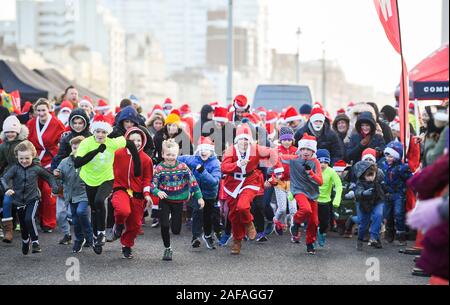 Brighton UK 14 décembre 2019 - Des centaines y compris les enfants et les chiens prennent part à la Brighton Santa Dash sur un jour de vent le long de la mer d'aider à recueillir des fonds pour la charité Rockinghorse qui est le bras de collecte de fonds de l'Hôpital Royal Alexandra d'enfants . Crédit : Simon Dack / Alamy Live News Banque D'Images