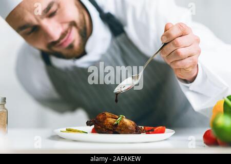 La cuisson des aliments Chef Pouring Sauce sur le plat de poulet dans la cuisine Banque D'Images