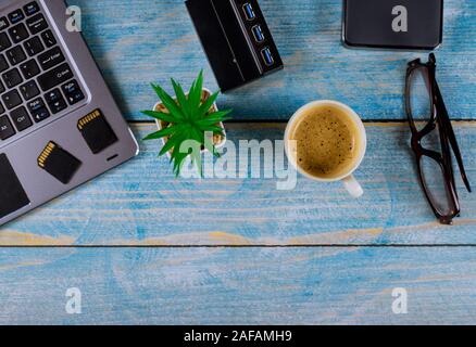 Fichier de sauvegarde chaque photographe d'utiliser le stockage externe disque dur et lecteur USB3.0 de mémoire cartes SD sur clavier d'ordinateur portable avec verres et café Banque D'Images