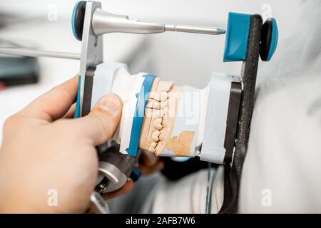 Technicien dentaire articulateur et travailler avec le modèle de la mâchoire au laboratoire, close-up view Banque D'Images
