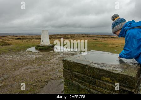 Personne portant un bobble hat regardant la carte directionnelle à l'trig point en haut de Baildon Moor, près de Bradford West Yorkshire Banque D'Images