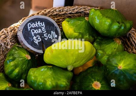 Une vue en gros plan d'un panier en osier rempli de patty casseroles, une variété de courge d'été, et le prix signe sur un stand lors d'une foire agricole Banque D'Images