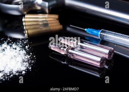 Un pistolet à balles, seringue et les médicaments se trouvent sur le tableau noir. Mauvaises habitudes dangereuses, la dépendance aux drogues et du jeu. Crime à cause de la drogue. La vente, Banque D'Images