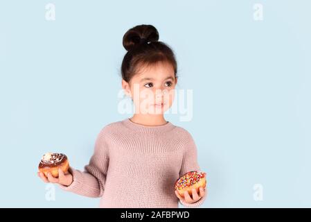 Peu de professionnels cute girl holding donuts sur fond bleu. Banque D'Images