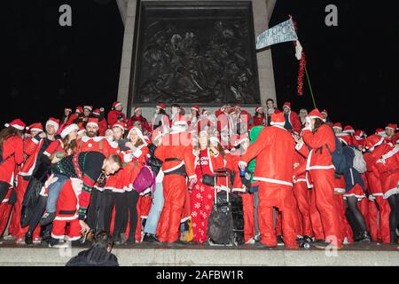 Trafalgar Square, Londres, Royaume-Uni. 14 décembre 2019. Des centaines de participants vêtus des costumes du Père Noël se rassemblent à Trafalgar Square, Londres, lors des festivités Santacon 2019. La scène nocturne met en scène une foule dense en tenue rouge et blanche, avec des accessoires ludiques et des bannières, dont une lisant « SANTARCHY ». L'image capture l'esprit humoristique et anarchique de la célébration annuelle costumée, avec pour toile de fond les monuments emblématiques de Londres et l'architecture publique. Penelope Barritt/Alamy Live News Banque D'Images