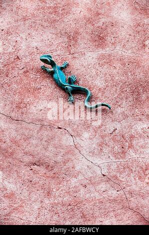 Un gecko vert décoration murale est placée sur un mur en stuc fissuré dans la ville de Roussilon en France. Banque D'Images