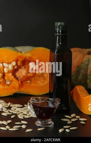 L'huile de citrouille en saucière et dans une bouteille sur un fond sombre, orientation verticale Banque D'Images