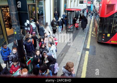 Groupe d'écoliers personnes attendant un bus lors d'une visite à Oxford Street à Londres Angleterre KATHY DEWITT Banque D'Images