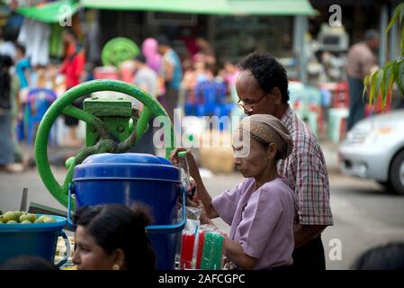 Vieille femme qui fait boire à la centrifugeuse de canne à sucre, Yangon, Myanmar Banque D'Images