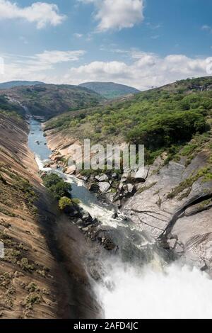 Le lac Mutirikwi (anciennement le lac Kyle), au Zimbabwe. L'eau s'écoule de la sortie du barrage de Mutirikwi dans une rivière située entre d'énormes collines de granit. Banque D'Images