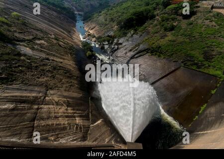 Le lac Mutirikwi (anciennement le lac Kyle), au Zimbabwe. L'eau s'écoule de la sortie du barrage de Mutirikwi dans une rivière située entre d'énormes collines de granit. Banque D'Images