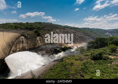 Le lac Mutirikwi (anciennement le lac Kyle), au Zimbabwe. L'eau s'écoule de la sortie du barrage de Mutirikwi dans une rivière située entre d'énormes collines de granit. Banque D'Images