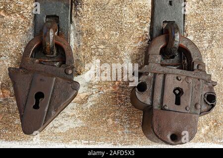 Close-up de deux anciennes cadenas rouillé avec poignée avec un mur de pierre sur l'arrière-plan Banque D'Images