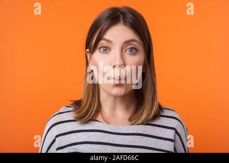 Portrait de jeune femme drôle avec les cheveux bruns en chemise rayée manches longues décisions permanent face poisson avec des lèvres, à la recherche et à l'appareil ludique enfantin Banque D'Images